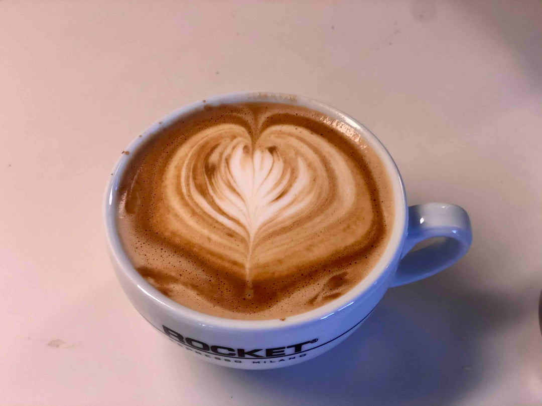 Latte prepared at an espresso machine illustrating the milk texture and surface used for heart latte art