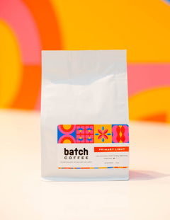 Batch Coffee Primary Light bag with orange and pink patterned label