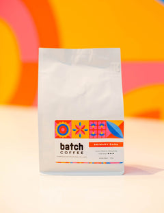Batch Coffee Primary Dark bag against an orange and pink background