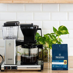 Barely Buzzed bag beside a filter coffee brewer and plant