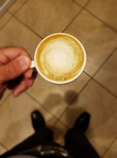 Overhead view of a hand holding a small milk coffee — Al Gusto Espresso Blend Dark Roast Coffee