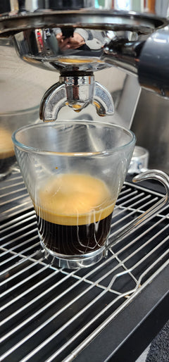 Espresso machine extracting coffee into a clear glass — Al Gusto Espresso Blend Dark Roast Coffee