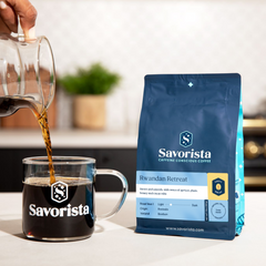 Pouring coffee into a glass mug beside Rwandan Retreat decaf