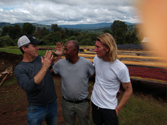 Three visitors tasting coffee beside drying beds — Tiny Footprint Ethiopia Suke Quto Honey Light Roast