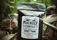 Black Allagash Ghost Trains bag beside old machinery in the woods