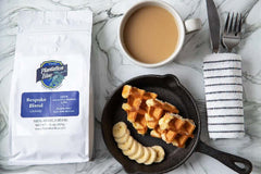 Bespoke ground bag alongside coffee, a striped napkin and a fruit-topped breakfast bowl