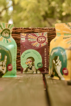Red Kafe Dondon bag with a portrait illustration among other Haiti Coffee packages