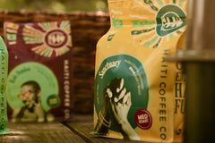 Yellow Sanctuary Haiti Coffee bag with a hand illustration beside a red Dondon package