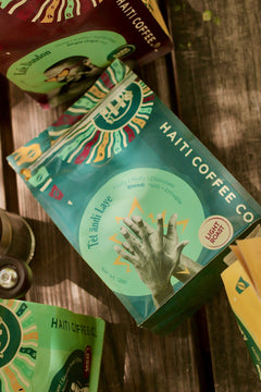 Teal Tèt āndi Laye coffee bag laid among Haiti Coffee packages on wooden boards