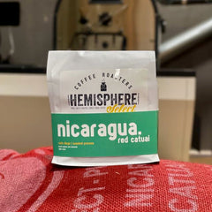 Nicaragua Red Catuai bag resting on a red coffee sack — Hemisphere Nicaragua Red Catuai Light Roast, 10 oz