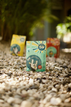 Front of a green Respè coffee package displayed outdoors on pale stones