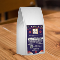 White Ironwood Blend bag with purple label on a wooden table — Al Gusto Ironwood Medium-Dark Coffee Blend