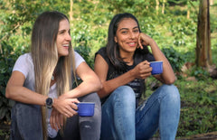 Two women seated outdoors with coffee mugs