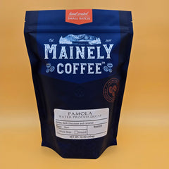 Blue Mainely Pamola decaf bag photographed against a yellow backdrop