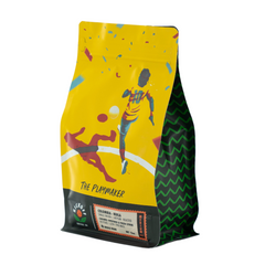 Yellow Playmaker coffee bag with illustrated soccer players at an angle — Kickoff The Playmaker Colombia Medium Roast Coffee