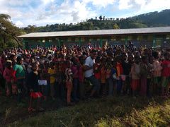 Large community gathering outside a long low building — Tiny Footprint Ethiopia Suke Quto Honey Light Roast