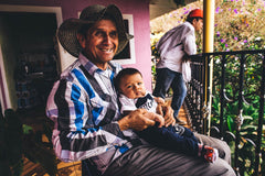 Olympia Decaf Asterisk Colombian Sugarcane Coffee — seated man holding a child on a porch