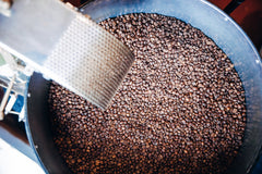 Roasted coffee beans in a cooling tray with a metal scoop — Clear Lake Surf Medium Roast Coffee Blend gallery