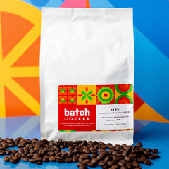 Batch Coffee Peru Sangareni bag with red and green label above roasted beans