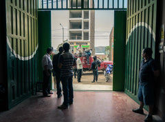 View through open green warehouse doors toward people outside — Tiny Footprint Peru Lima Cafe Medium Roast Coffee