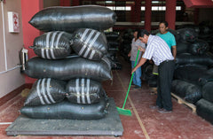 People beside tall piles of coffee sacks in a warehouse — Tiny Footprint Peru Lima Cafe Medium Roast Coffee