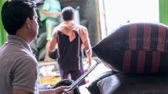 People moving sacks near an open loading doorway — Tiny Footprint Peru Lima Cafe Medium Roast Coffee