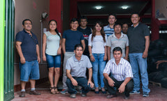 Group portrait of people standing and seated in a warehouse doorway — Tiny Footprint Peru Lima Cafe Medium Roast Coffee