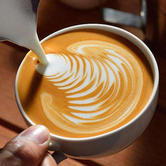 Passport Portofino Medium-Light Espresso Coffee — milk poured into a cup to form leaf-pattern latte art